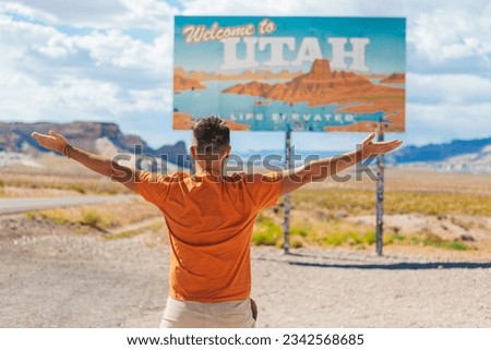 Happy man on trip to the USA on the background of Welcome to Utah State border sign right in the National Canyon, USA