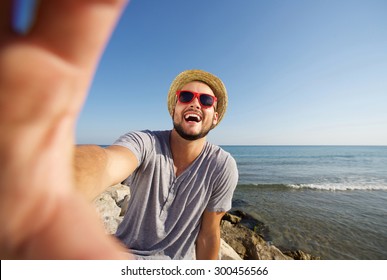 Happy man on vacation laughing at the beach taking selfie - Powered by Shutterstock