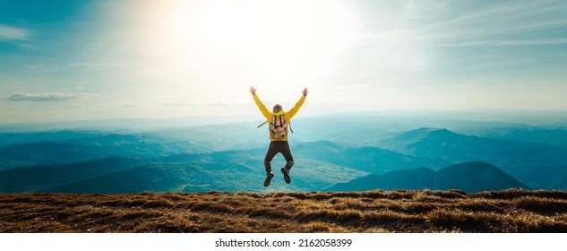 Happy Man With Open Arms Jumping On The Top Of Mountain - Hiker With Backpack Celebrating Success Outdoor - People, Success And Sport Concept