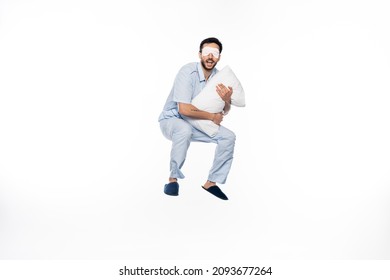 Happy Man In Pajamas And Sleeping Mask Levitating With Pillow On White