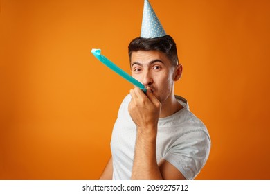 Happy man with party cone blowing into party horn - Shutterstock ID 2069275712