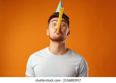 Happy Man With Party Cone Blowing Into Party Horn