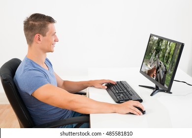 Happy Man Playing Game On Desktop Computer At Desk