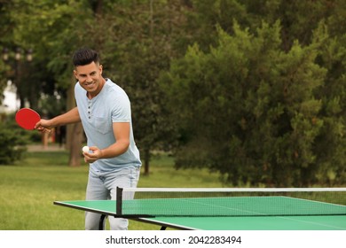 Hombre feliz jugando ping pong al aire libre en verano