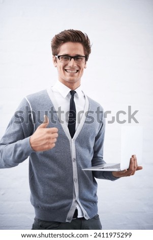 Happy man, portrait and laptop with thumbs up for winning or good job on a gray studio background. Male person, nerd or geek smile with computer, like emoji or yes sign for approval on mockup space