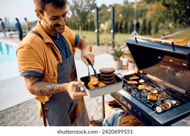 Happy man preparing food on barbecue grill in the backyard.  - Powered by Shutterstock