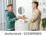 Happy man presenting gift to his brother at home