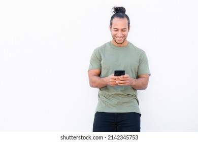 Happy Man With Pulled Up Hair Bun Text Messaging Using Mobile Phone Over White Background
