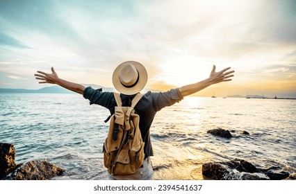 Happy man raising arms up enjoying sunset on the beach - Delightful traveler standing with hands up looking morning sunrise - Self care, traveling, wellness and healthy life style concept - Powered by Shutterstock