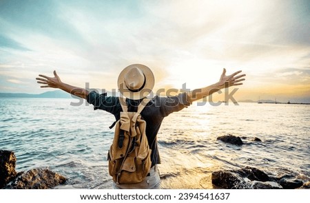 Happy man raising arms up enjoying sunset on the beach - Delightful traveler standing with hands up looking morning sunrise - Self care, traveling, wellness and healthy life style concept