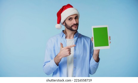 happy man in red santa hat pointing with finger at digital tablet with green screen isolated on blue  - Powered by Shutterstock