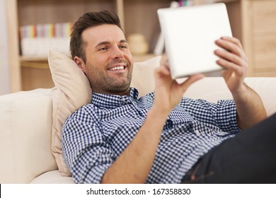 Happy Man Relaxing On Sofa With Digital Tablet 