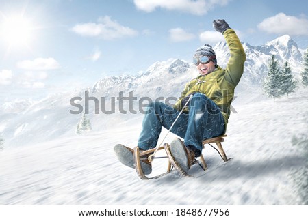 Happy man riding on a sled in winter