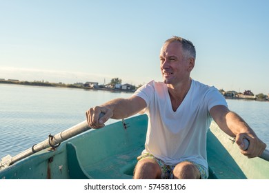 Happy man is rowing on a small boat in a calm sea and enjoying life, quiet sunny morning on the coast. - Powered by Shutterstock