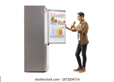 Happy man with a sandwich standing in front of a fridge isolated on white background