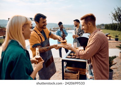 Happy man serving hamburgers to his friends during barbecue poolside party in the backyard. - Powered by Shutterstock