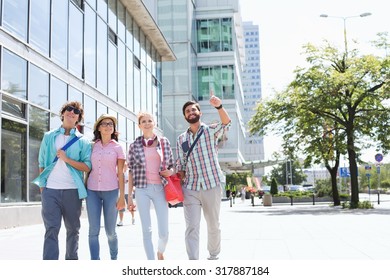 Happy Man Showing Something To Friends While Walking In City