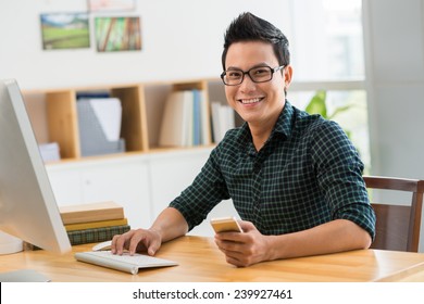 Happy man sitting at his workplace looking at the camera