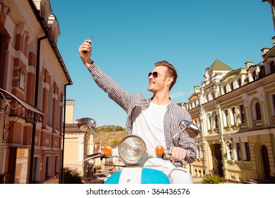 Happy man sitting on the scooter making selfie photo