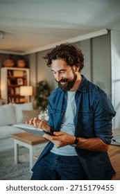 Happy man smiling while browsing digital tablet at home