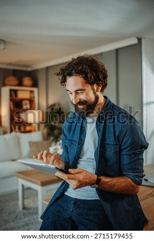 Happy man smiling while browsing digital tablet at home