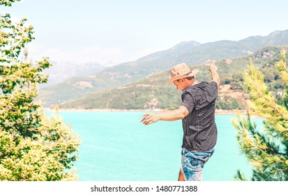 Happy man spreading arms and enjoying life in the mountain. Carefree guy with cowboy style hat feeling free. Journey to success. Freedom and fun lifestyle. Adventure in nature. Summer trip in valley.