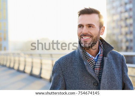 Happy man standing outdoors during sunny winter day