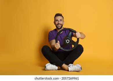 Happy Man With Steering Wheel On Yellow Background