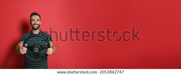 Happy man with
steering wheel on red
background