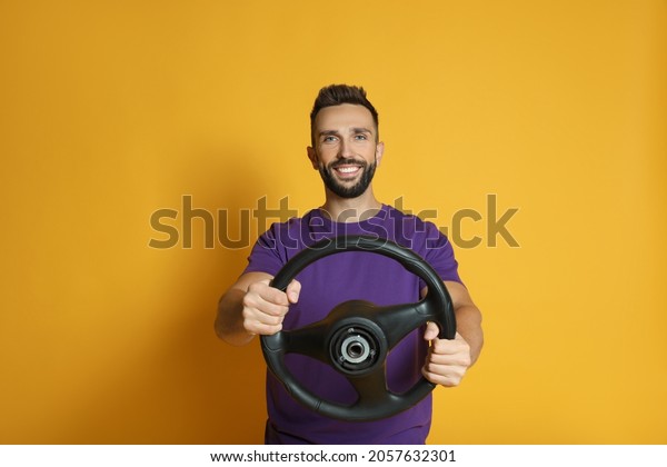 Happy man\
with steering wheel on yellow\
background