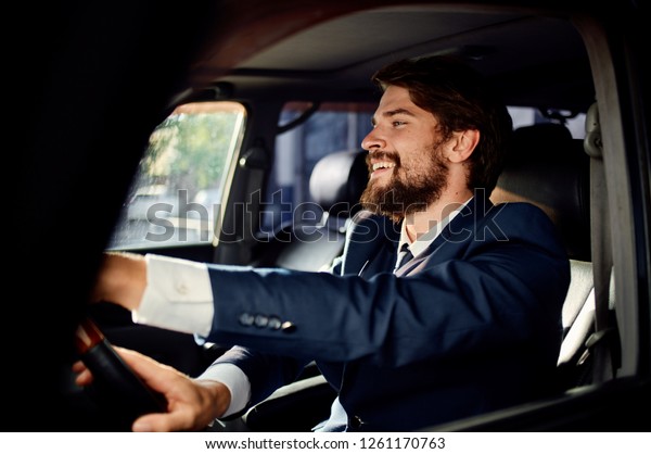 Happy man in a suit sits behind the wheel of a car      \
       