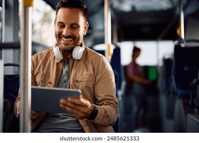 Happy man surfing the net on touchpad while riding in a bus. Copy space. - Powered by Shutterstock