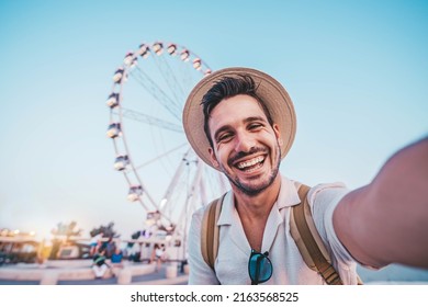 Happy man taking selfie walking on city street - Male tourist having fun on summer vacation - Smiling guy looking at camera outside - Focus on eye