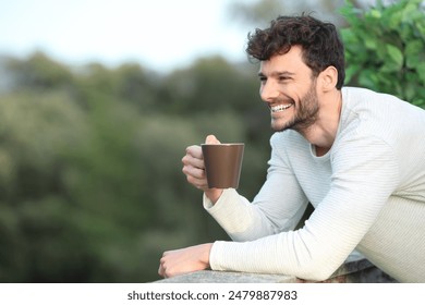 Happy man in a terrace drinking coffee looking away at home - Powered by Shutterstock