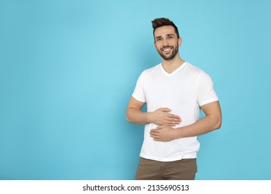 Happy Man Touching His Belly On Light Blue Background, Space For Text. Concept Of Healthy Stomach