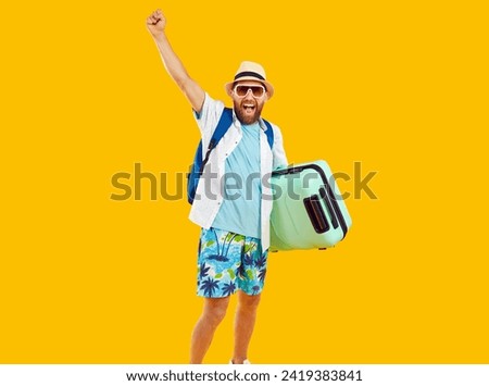 Happy man tourist in summer beach attire, isolated on orange background. With a suitcase and backpack in tow, he exudes the excitement of embarking on a well deserved vacation or holiday.