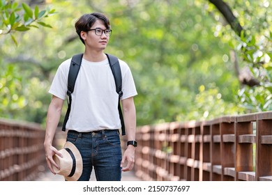 Happy man travel mangrove forest. Tourist traveler wear white shirt with hat for backpack activity. asian man ready to go hiking. Relax time on holiday concept travel.