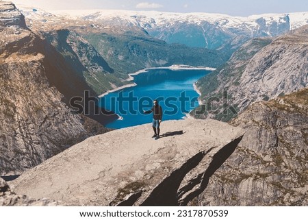Happy man, traveler on the wonder rock of Trolltunga, troll language. Sights of the Scandinavian mountains. The amazing and beautiful world of nature in Norway.