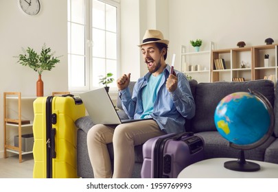 Happy Man Traveler Sitting On Home Sofa With Packed Luggage Suitcase Rejoice Successful Online Ticket Booking Or Hotel Reservation Holiday Vacation With Sale Discount Via Laptop Computer