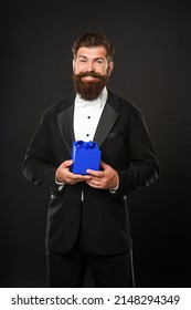 Happy Man In Tuxedo Bow Tie Formalwear On Black Background With Gift Box. Boxing Day