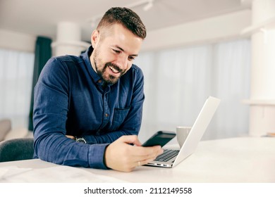 A happy man typing messages or dialing on his mobile phone at his cozy home. - Shutterstock ID 2112149558