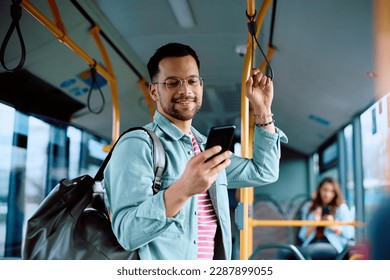 Happy man using app on cell phone while riding in a bus. 