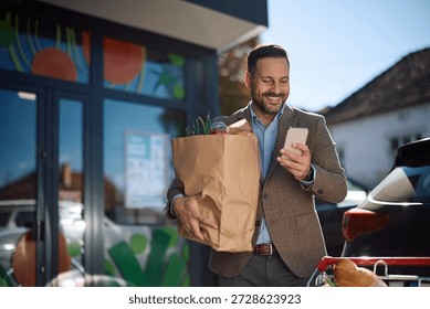Happy man using app on mobile phone while shopping in a supermarket.  Copy space.
