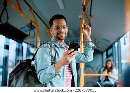 Happy man using app on cell phone while riding in a bus. 