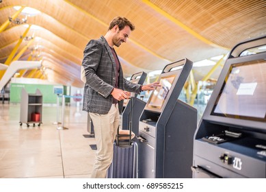 happy man using the check-in machine at the airport getting the boarding pass.