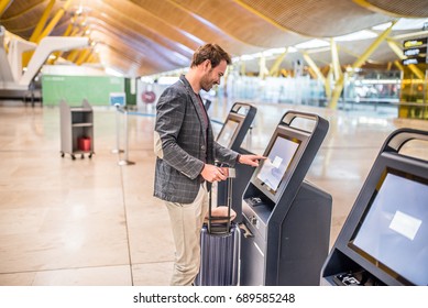 happy man using the check-in machine at the airport getting the boarding pass.