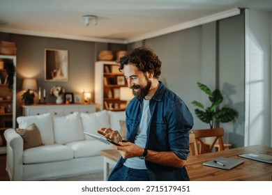 Happy man using a digital tablet for online browsing in a cozy living room