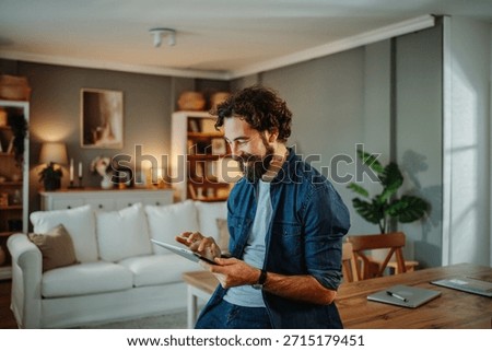 Happy man using a digital tablet for online browsing in a cozy living room