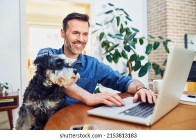 Happy man using laptop working from home with dog sitting on lap - Powered by Shutterstock