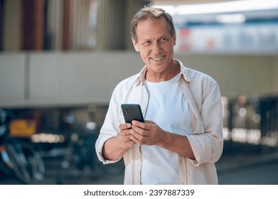 Happy man using smartphone browsing web pages phone in city.